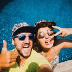 Paar mit Sonnenbrillen macht Selfie vor ihrem Pool